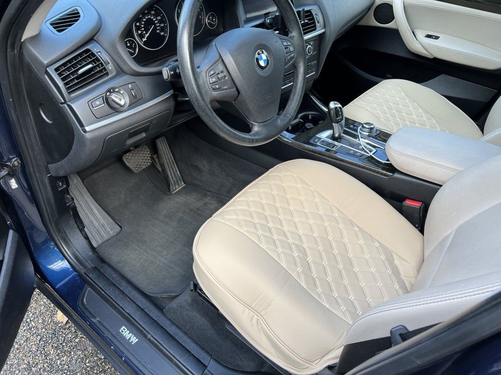 BMW car interior with beige seats, black dashboard, steering wheel, and open driver’s door