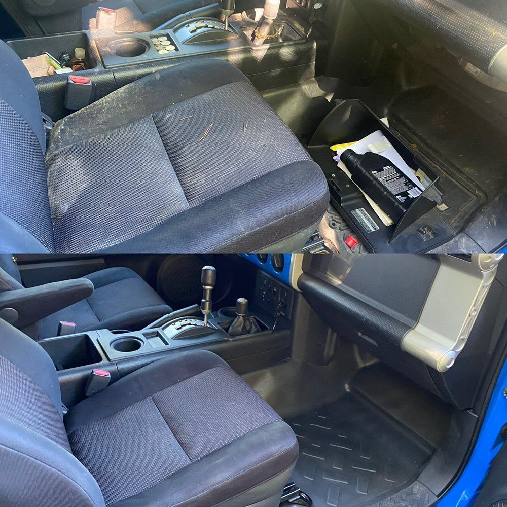 Car interior with black seats and center console, showing an open compartment with a battery or tool kit.