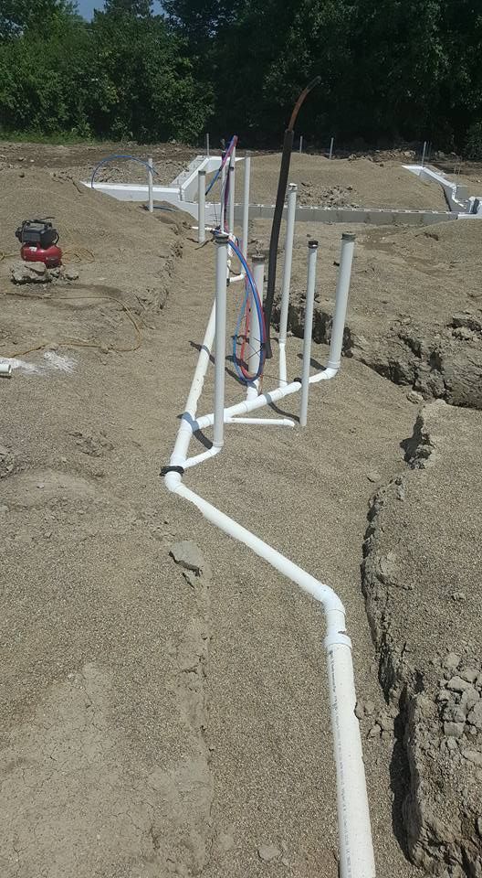 PVC pipes installed in trenches on a construction site, likely for plumbing.