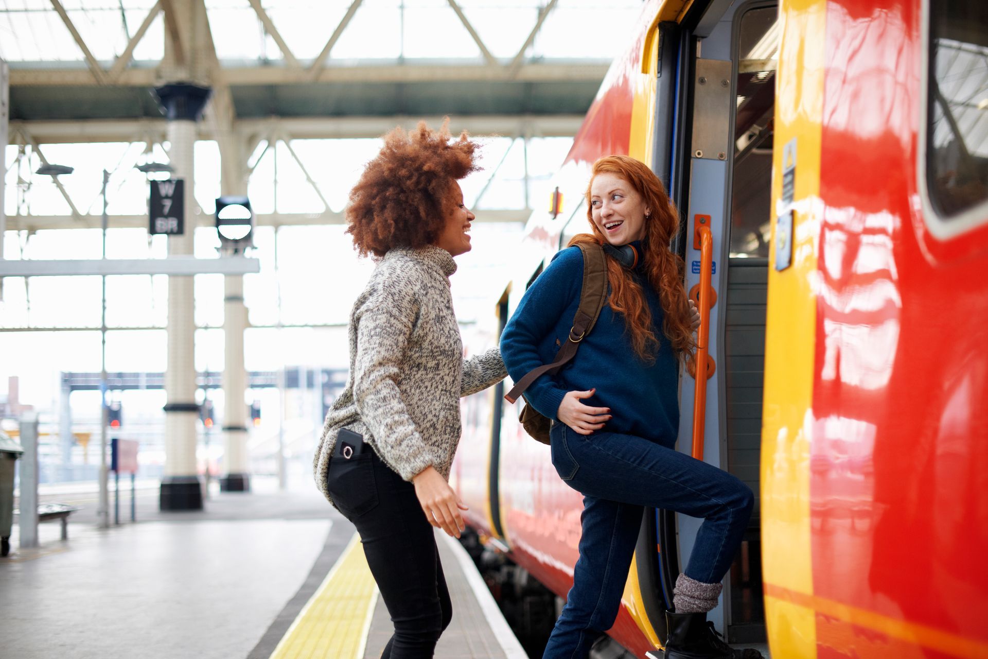 Two people boarding a colorful train at a station platform