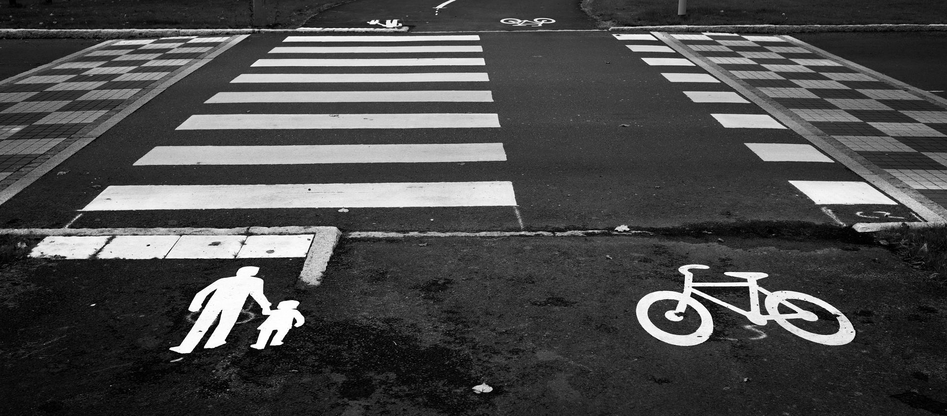 Crosswalk with pedestrian and bicycle symbols painted on the road at an intersection