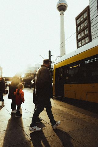 People walking beside a bus at sunset, with a tall tower in the background.