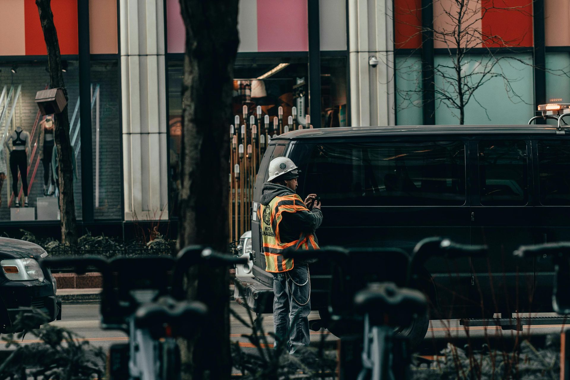 A man in a hard hat is standing next to a van on a city street.