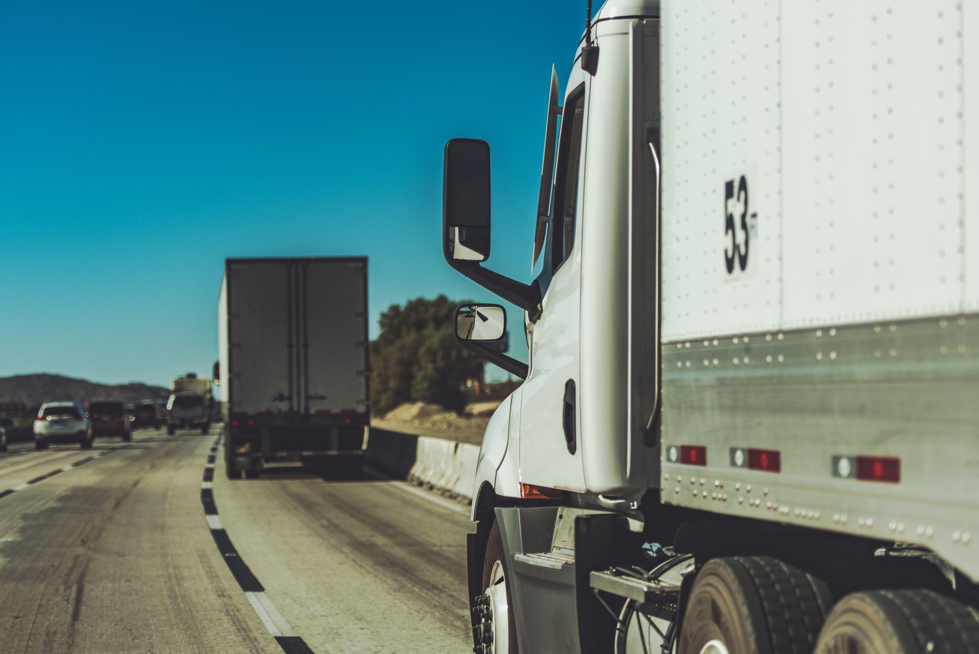 Semi-trucks driving on a highway under a clear blue sky