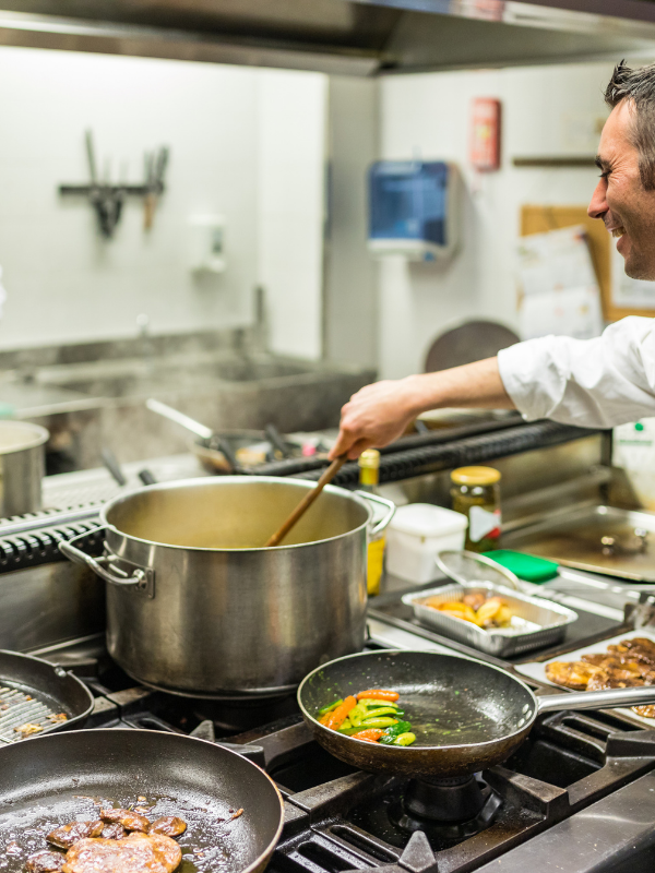 Un hombre está cocinando comida en una cocina con ollas y sartenes.