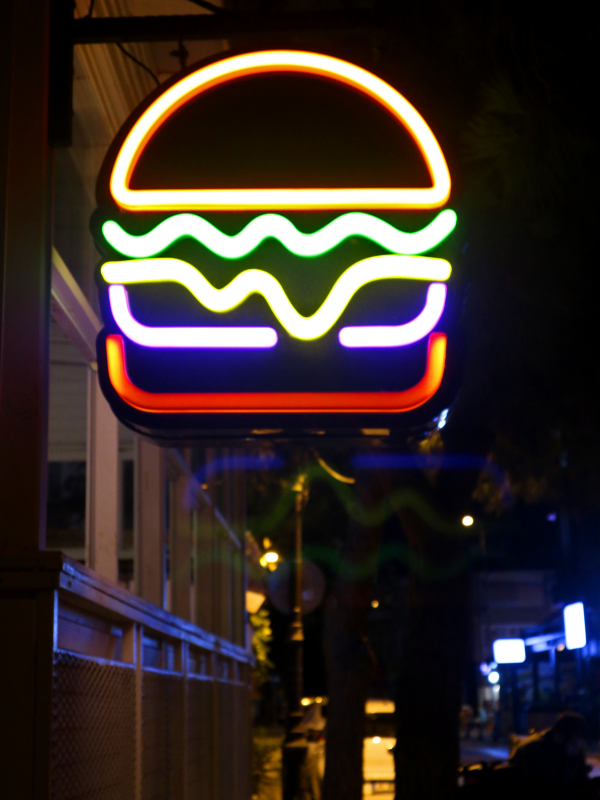 Un letrero de neón de una hamburguesa se enciende por la noche