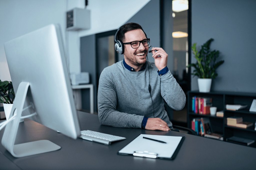 Un hombre con auriculares está sentado en un escritorio frente a una computadora.