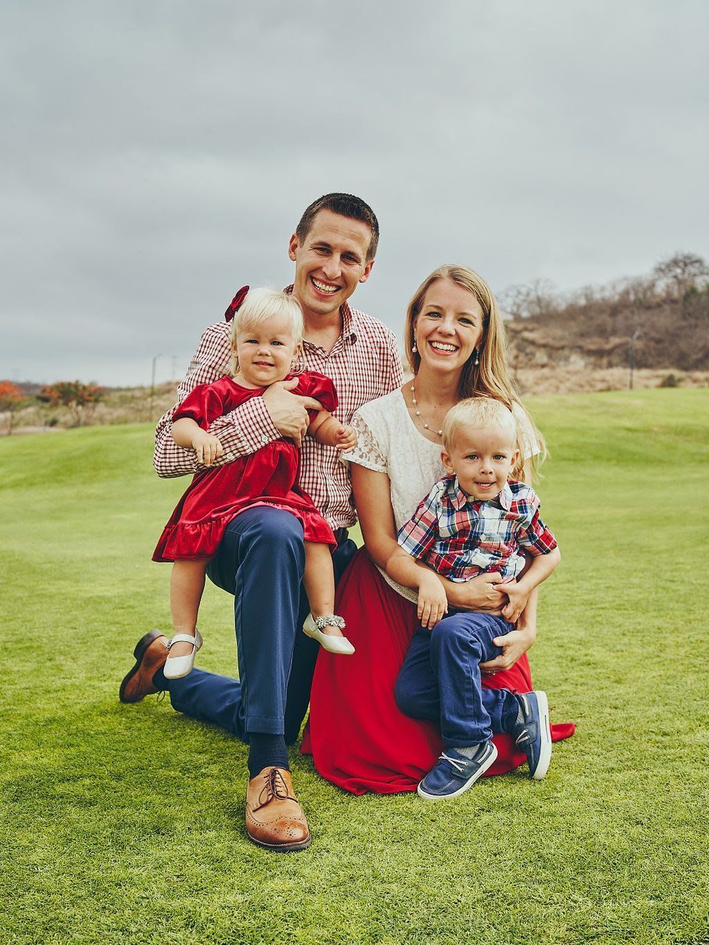 A family is posing for a picture on a lush green field.