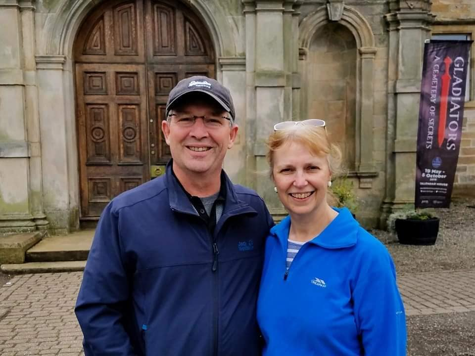 A man and a woman are posing for a picture in front of a building.