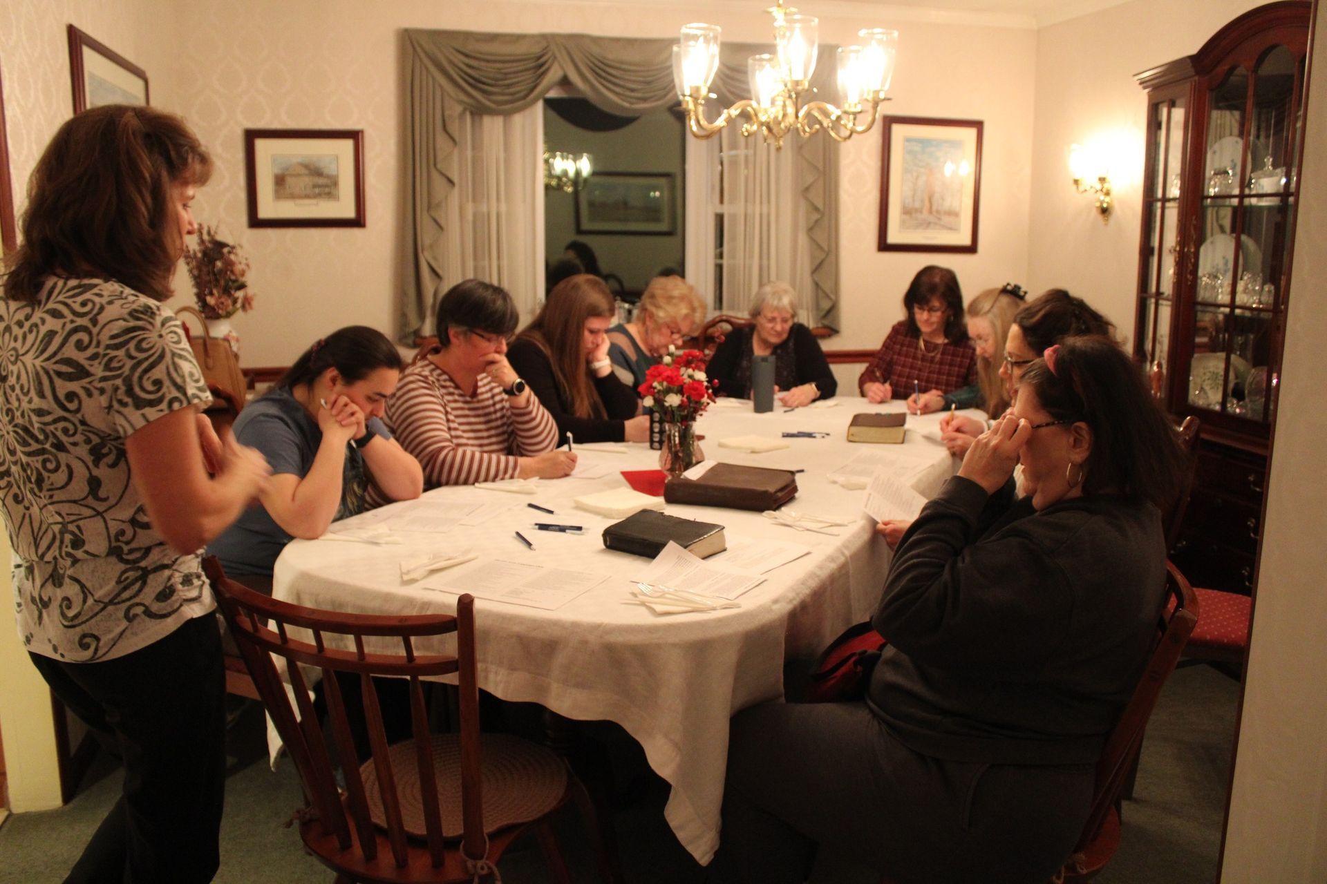 A group of people are sitting around a table with a bible on it