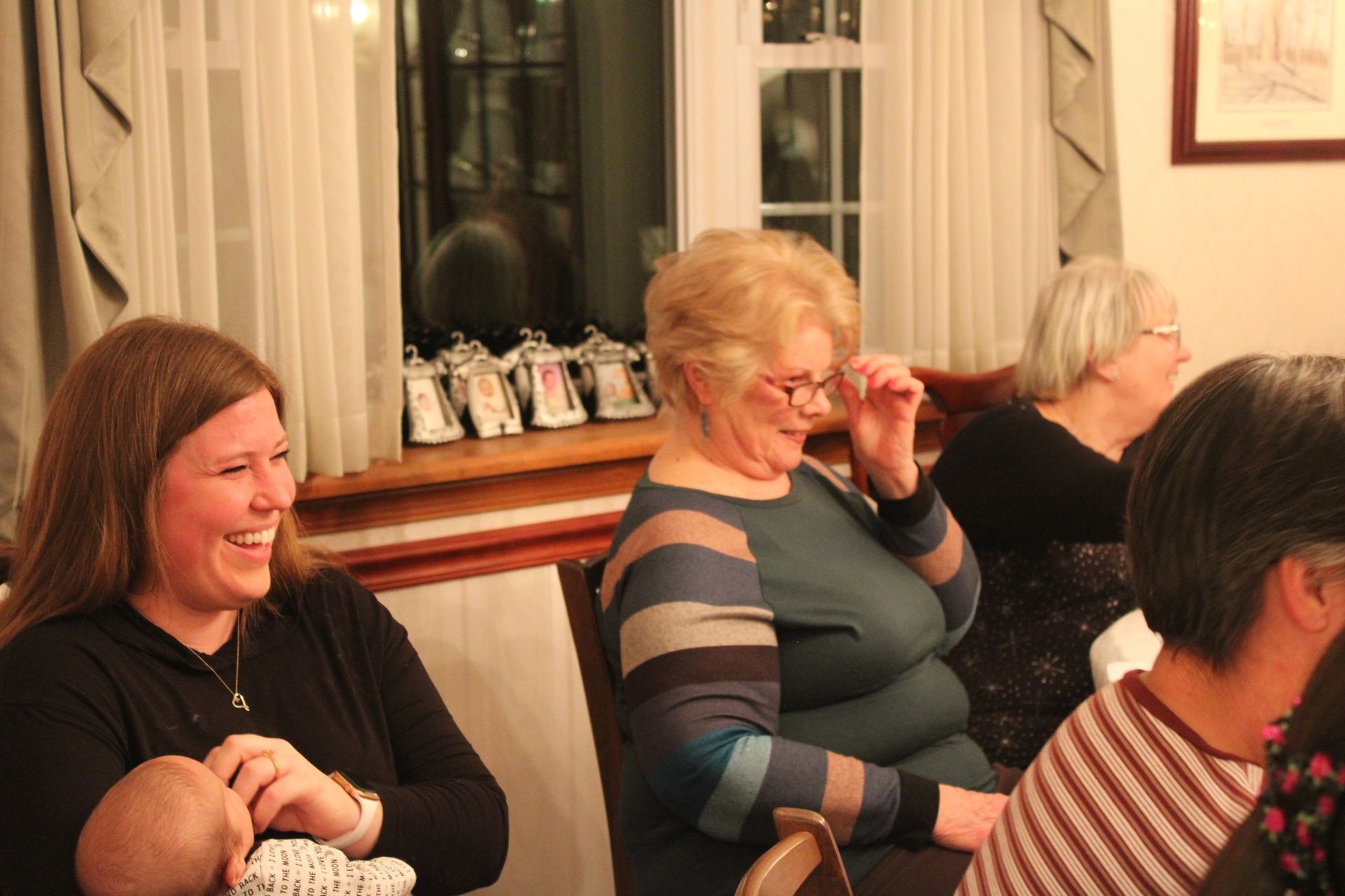 A group of women are sitting at a table with a baby.