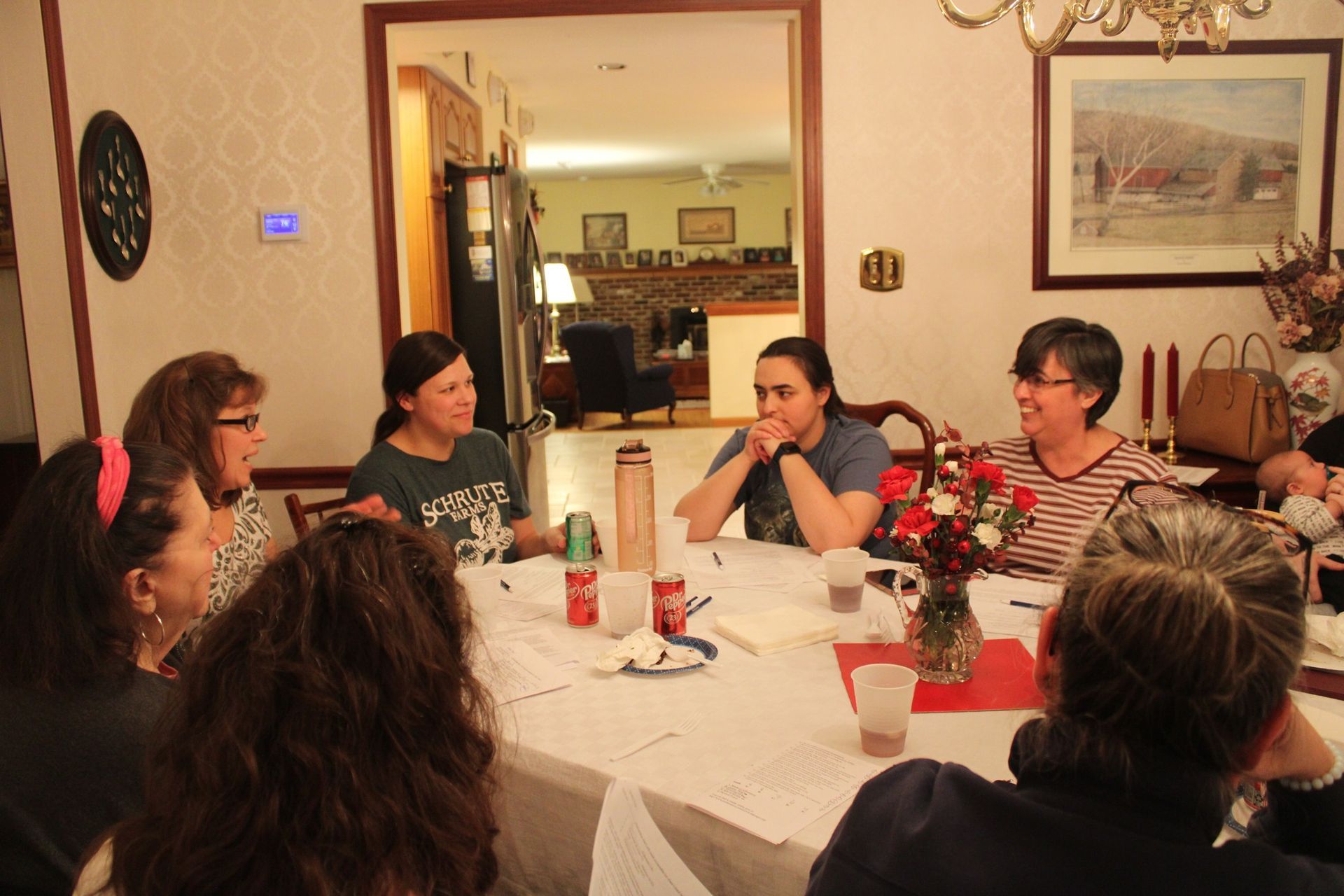 A group of people are sitting around a table in a living room