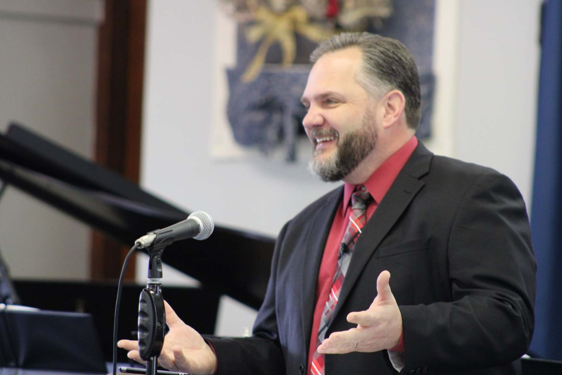 A man in a suit and tie is speaking into a microphone