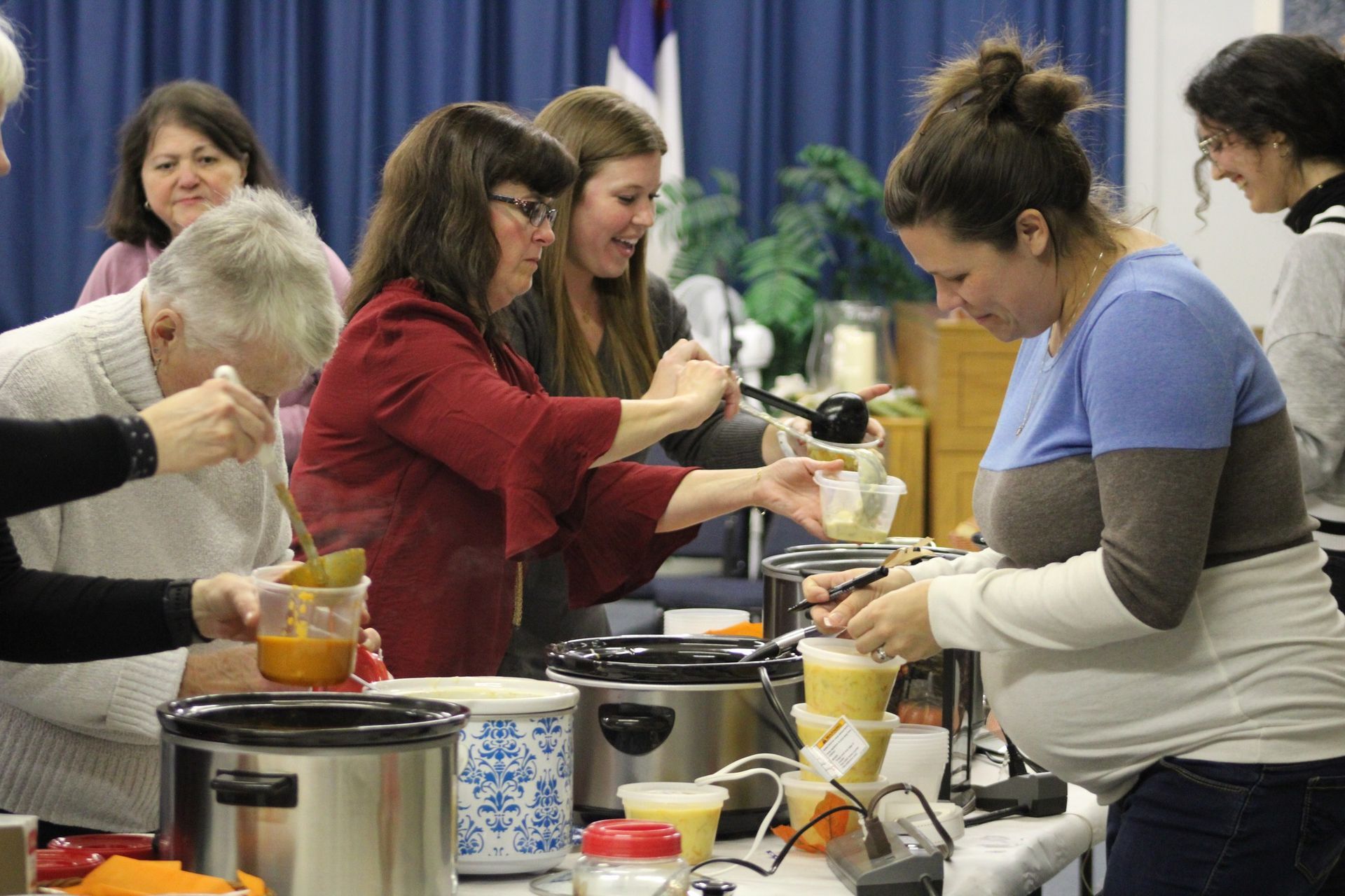 A group of people are preparing food in crock pots.