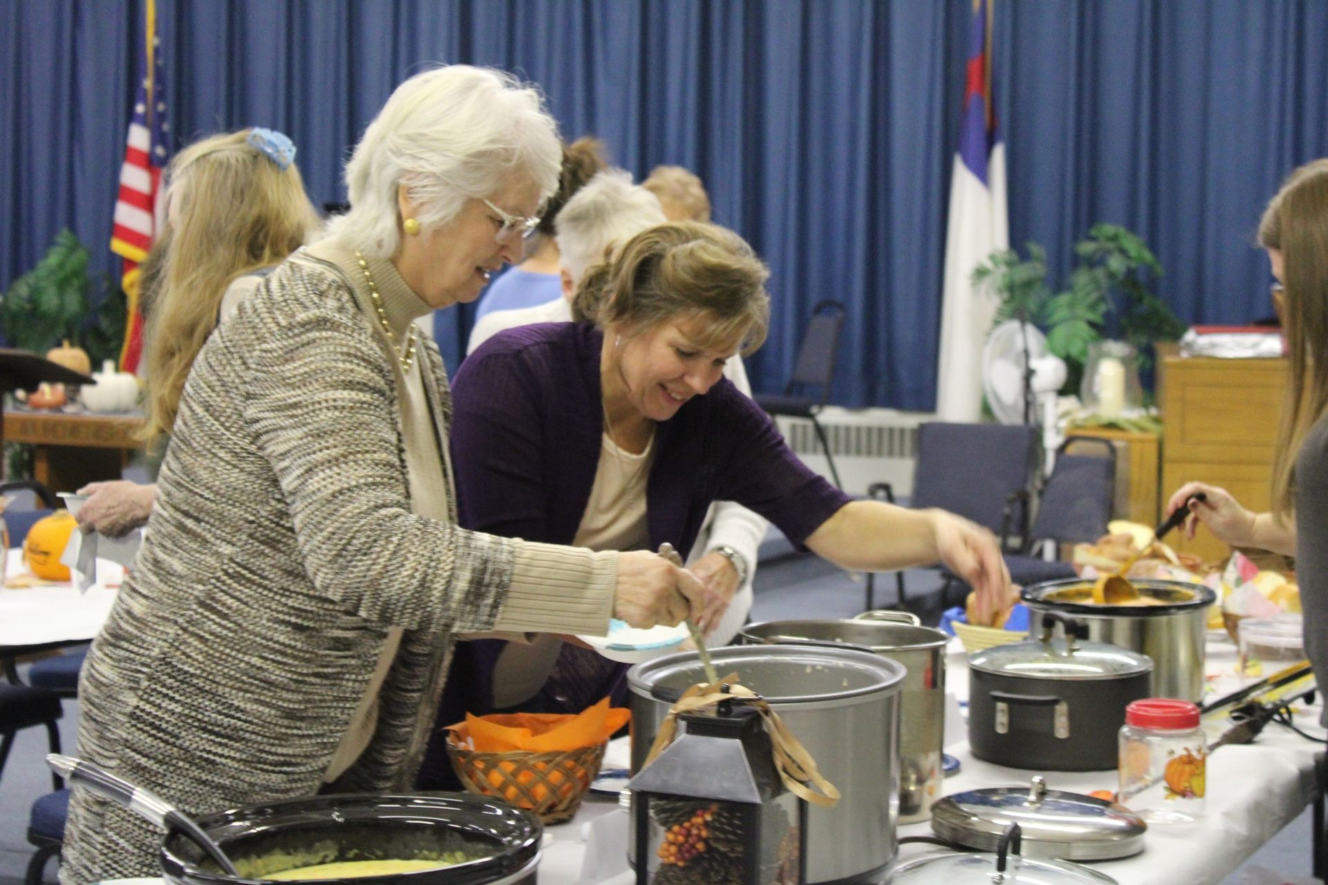 A group of women are standing around a table preparing food.