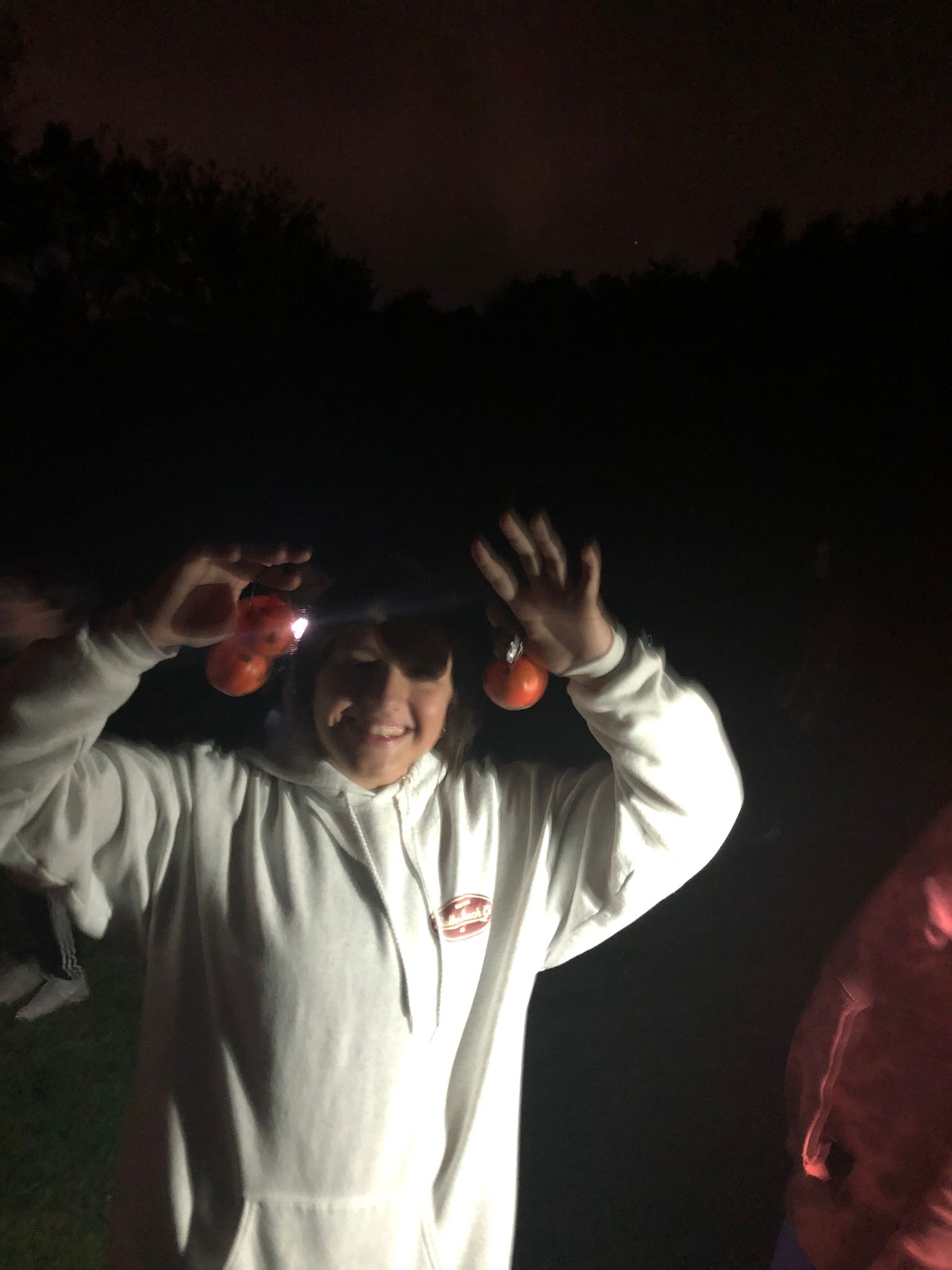 A person in a white hoodie is holding a flashlight over their head.