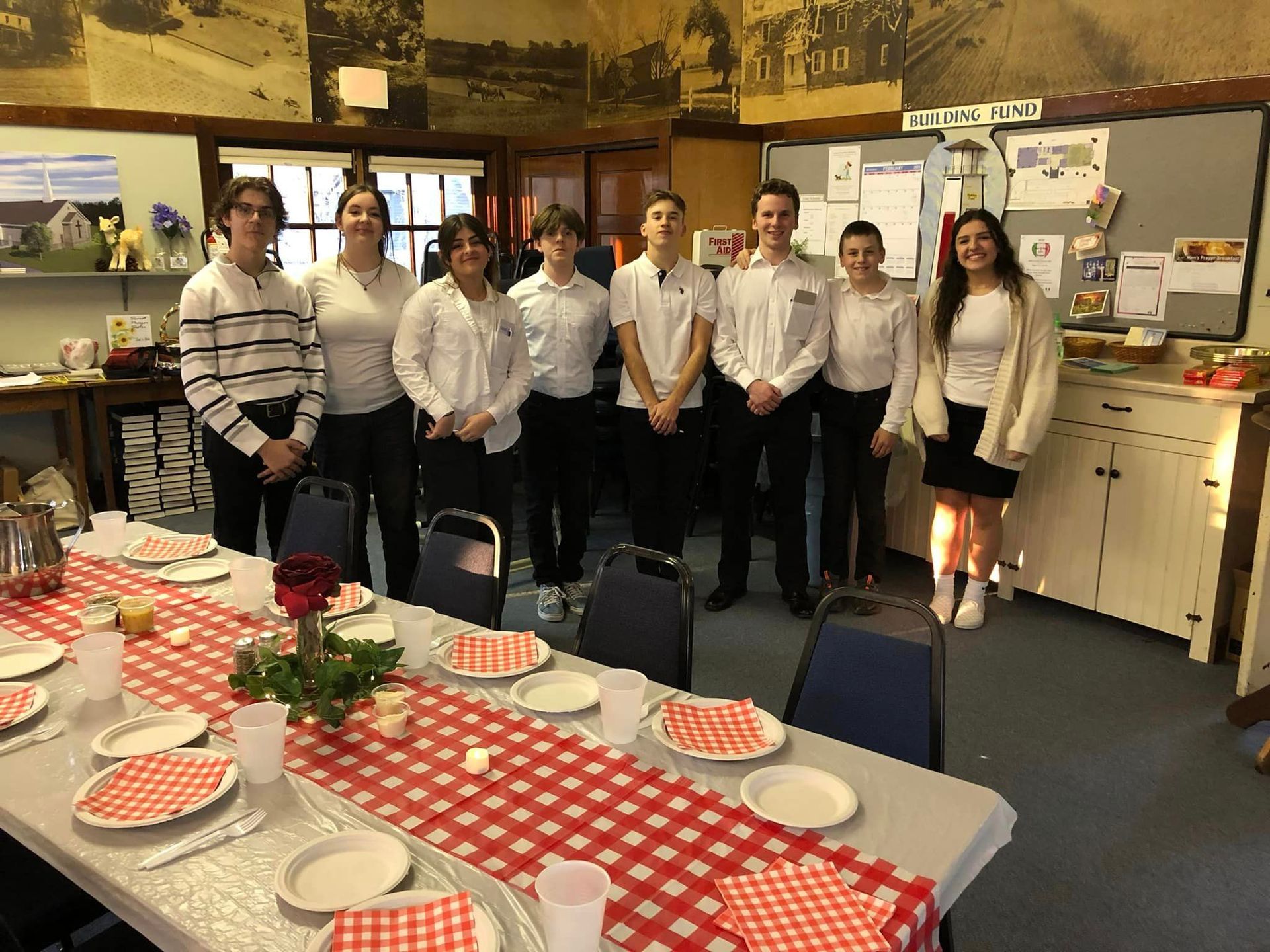 A group of people standing around a table with plates and napkins on it.