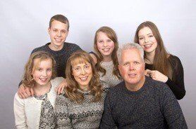 A family is posing for a picture together and smiling for the camera.