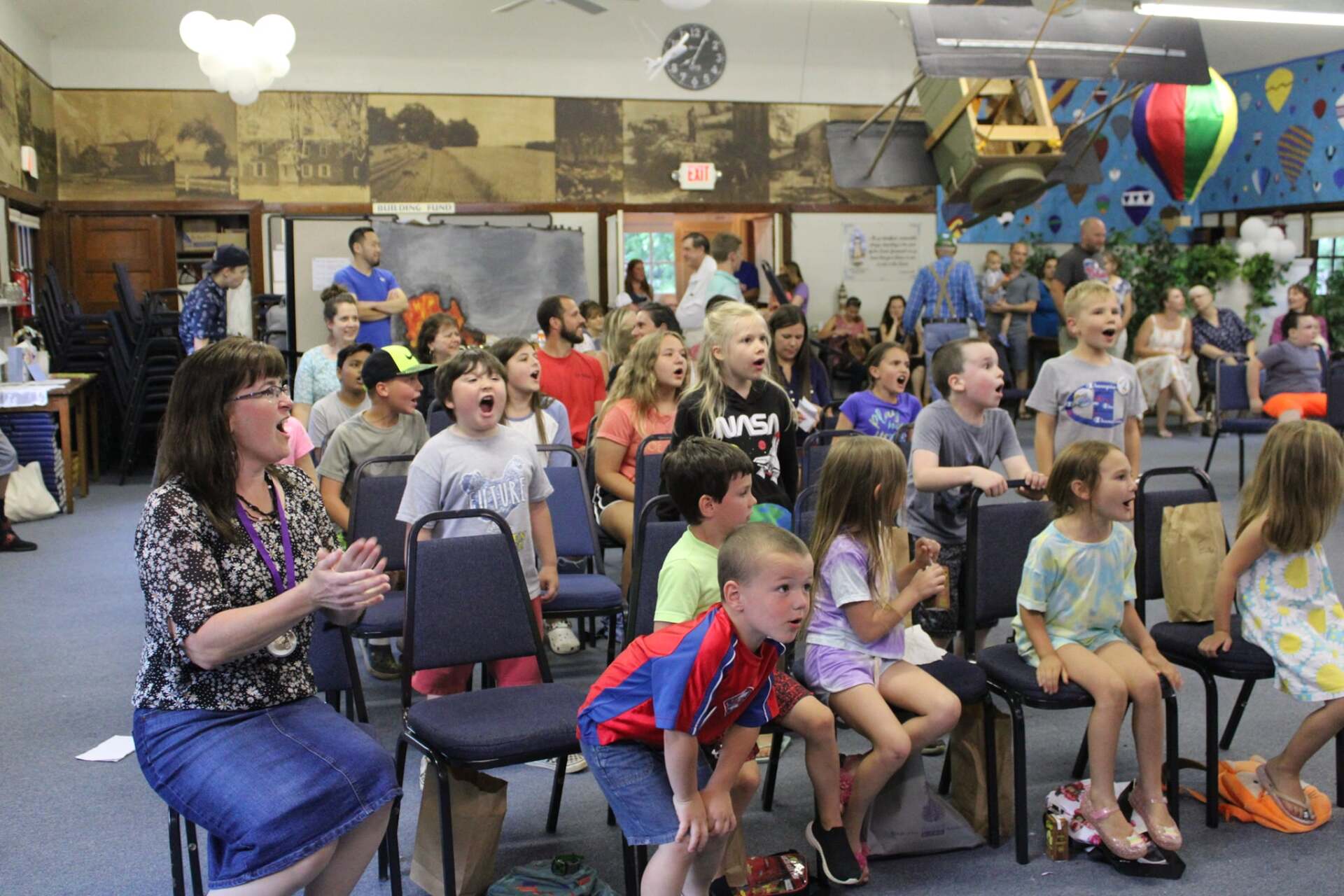 A group of children are sitting in chairs in a room.