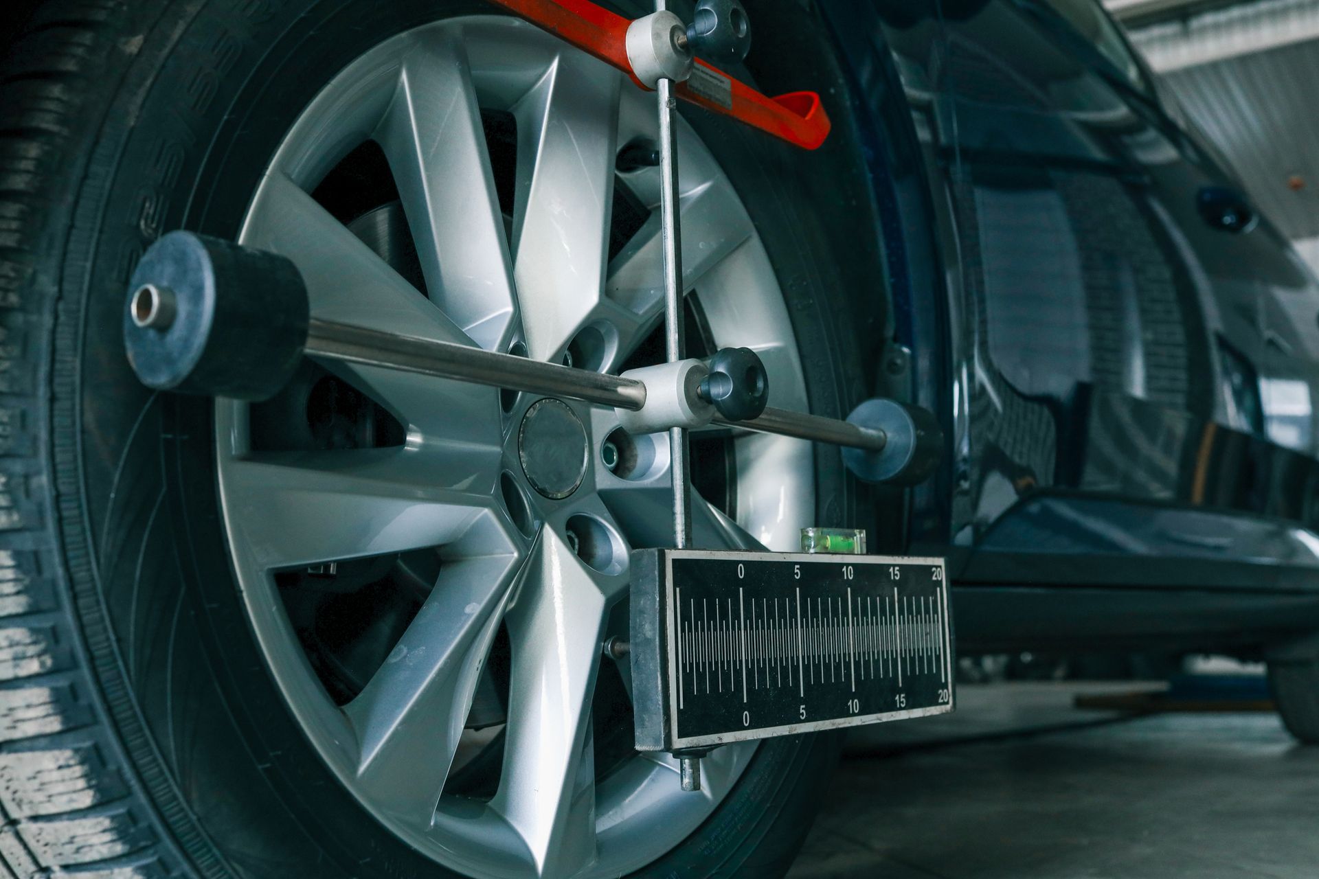 Car wheel being aligned with a gauge, showing a mechanic's shop setting.