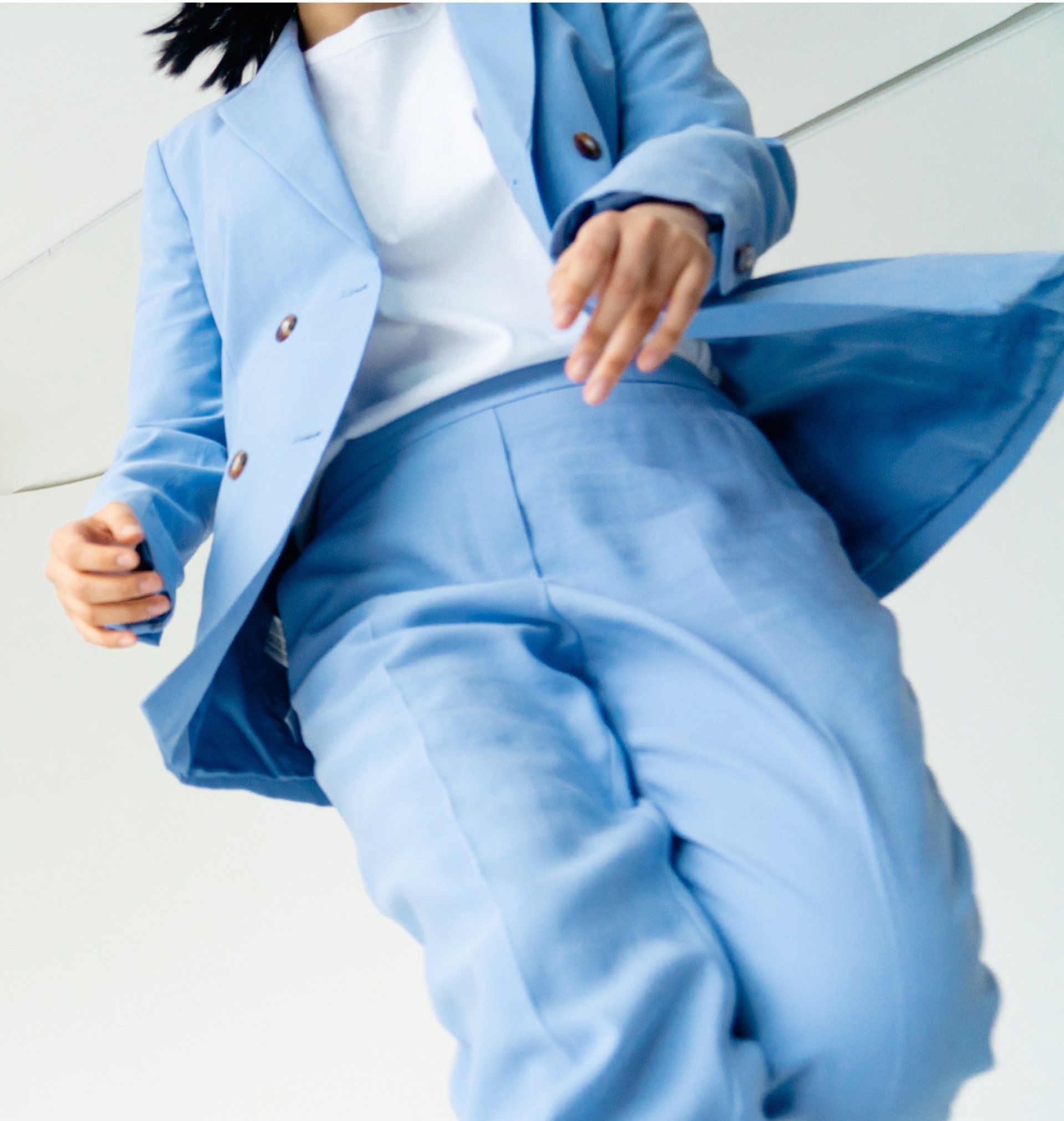 Woman wearing a blue blazer and pants over a white shirt, standing against a white backdrop.