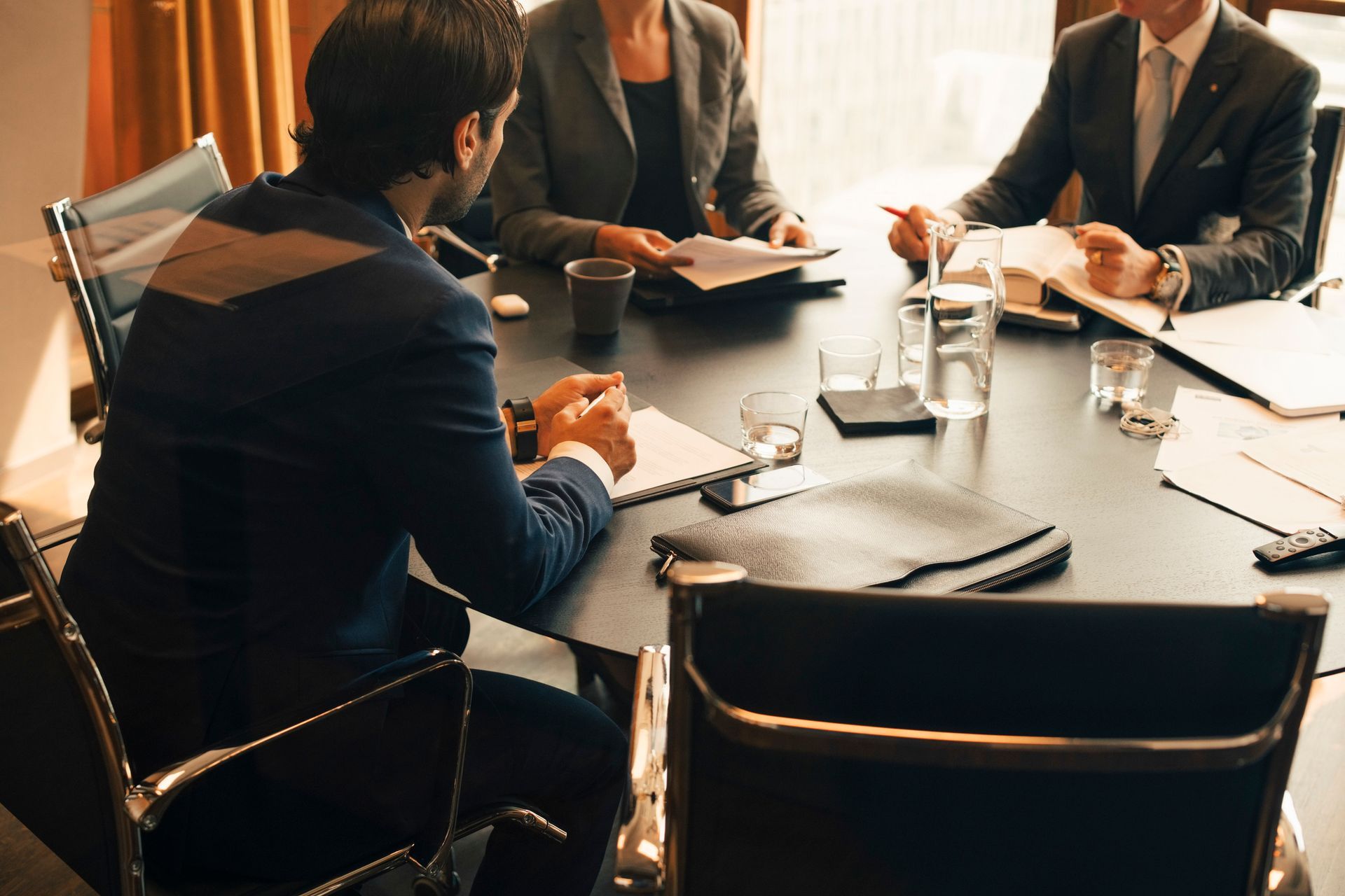 Businesspeople in suits at a conference table, discussing documents.
