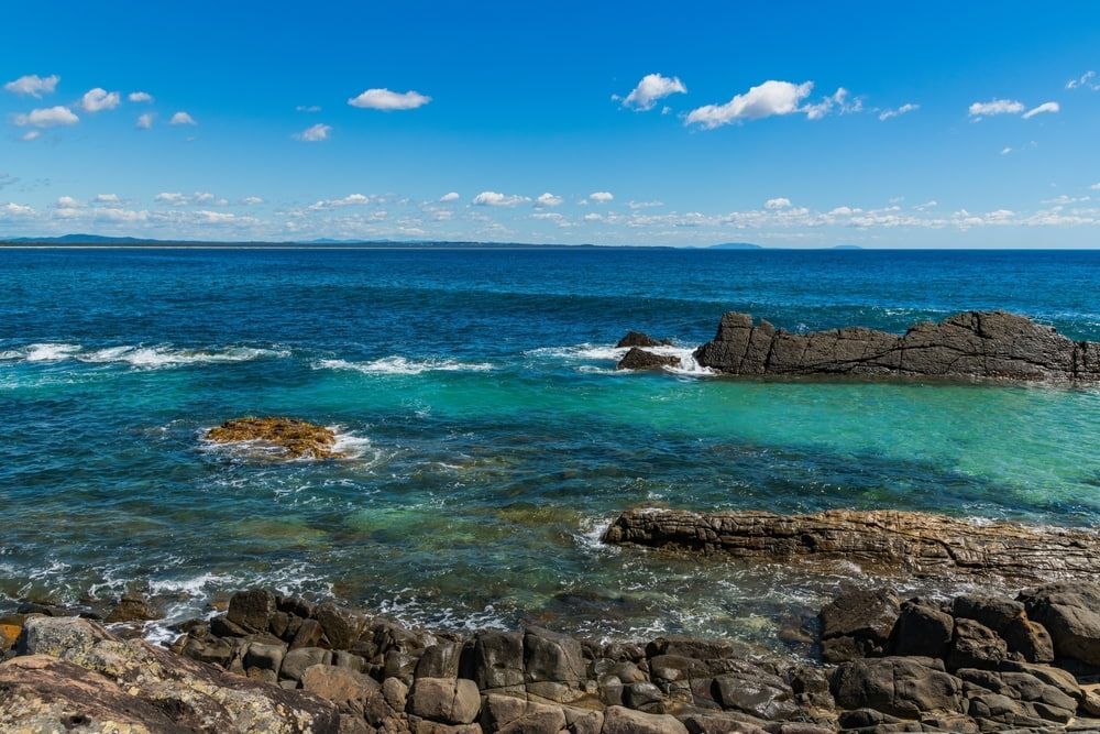 A View of The Ocean from A Rocky Shoreline on A Sunny Day In Tuncurry — D-Scapes Landscaping Services Pty Ltd in Forster, NSW 