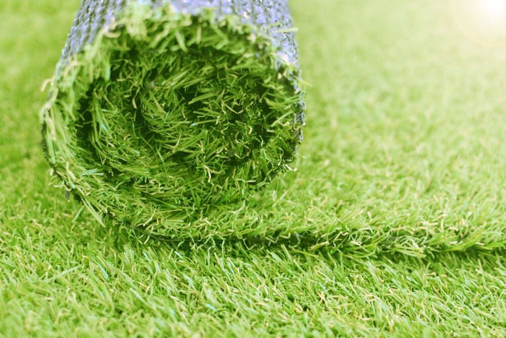 A Roll of Artificial Grass Is Sitting on Top of A Lush Green Field — D-Scapes Landscaping Services Pty Ltd in Forster, NSW