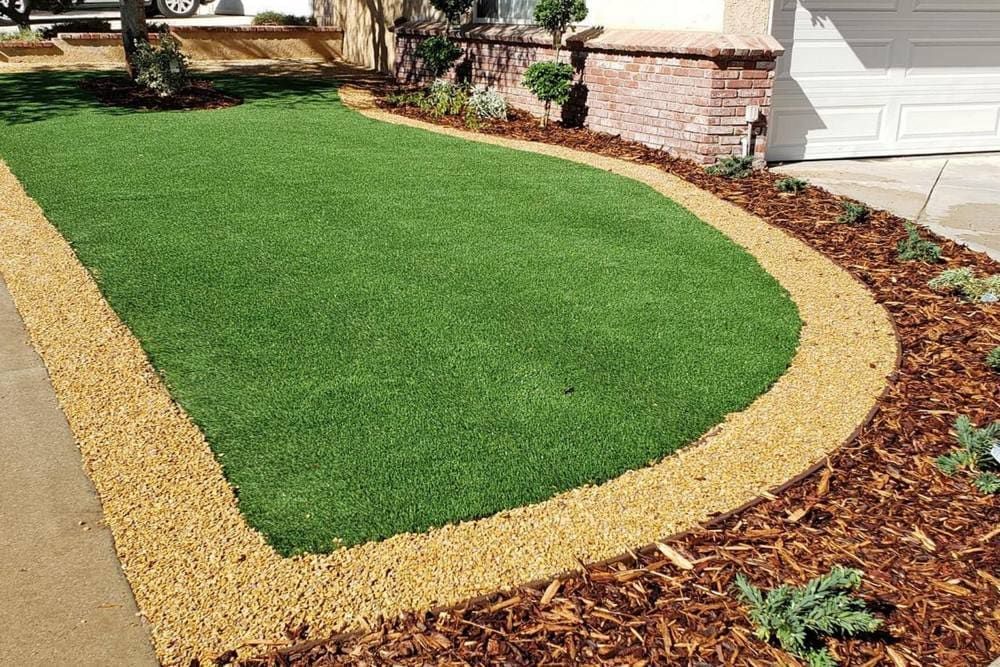 A Lawn with A Border of Gravel and Mulch in Front of A House — D-Scapes Landscaping Services Pty Ltd in Taree, NSW