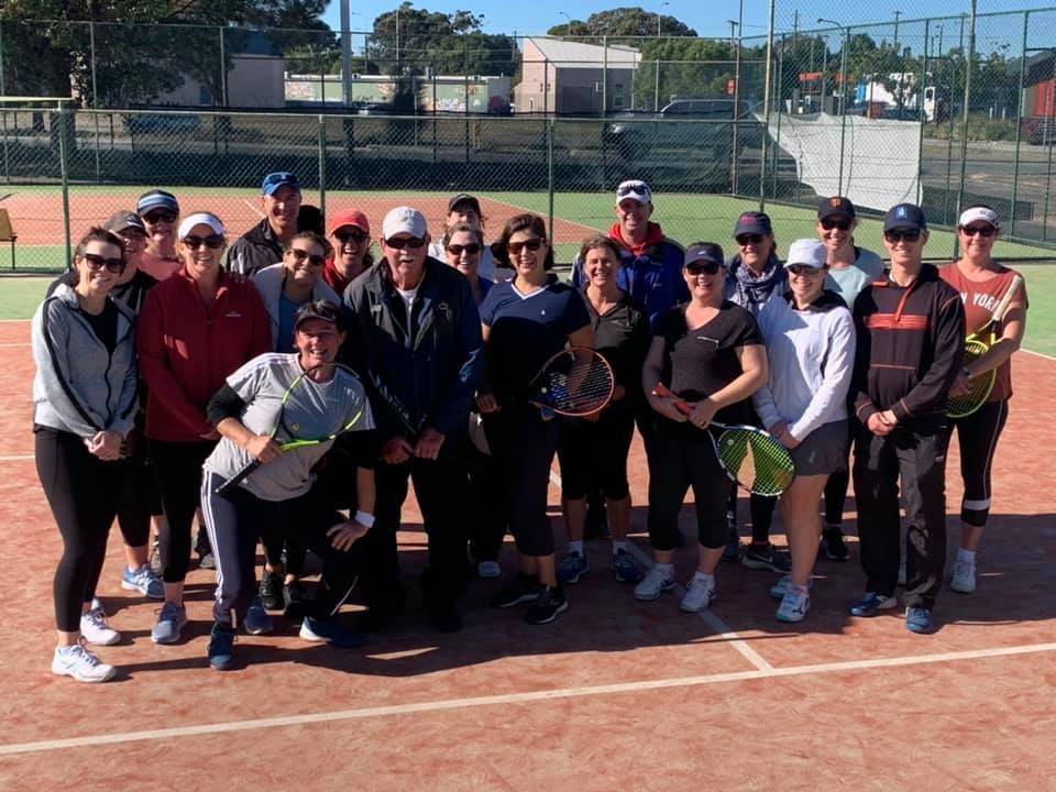 Group of People Pose on a Clay Tennis Court, Many Wearing Hats — Topspin Tennis Newcastle in Adamstown, NSW