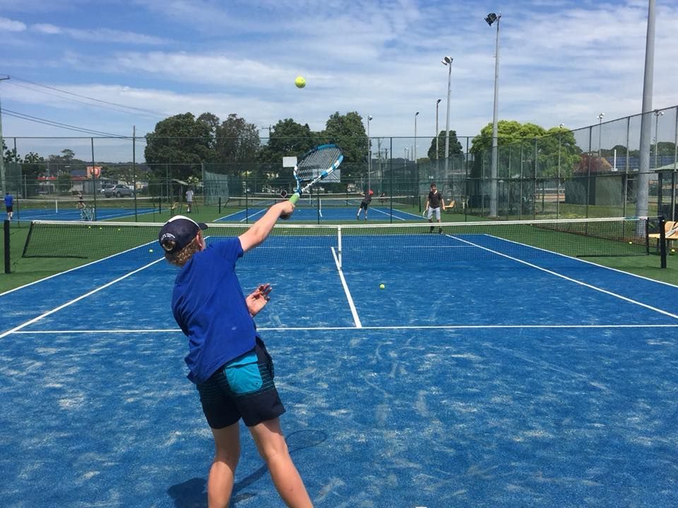 Boy in Blue Shirt Serving Tennis on a Blue Court — Topspin Tennis Newcastle in Lambton, NSW