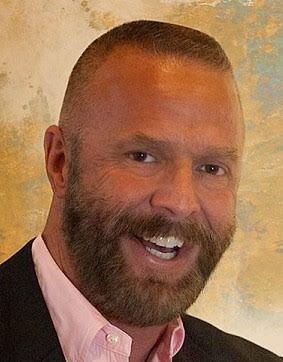 A man with a beard and mustache is smiling for the camera.