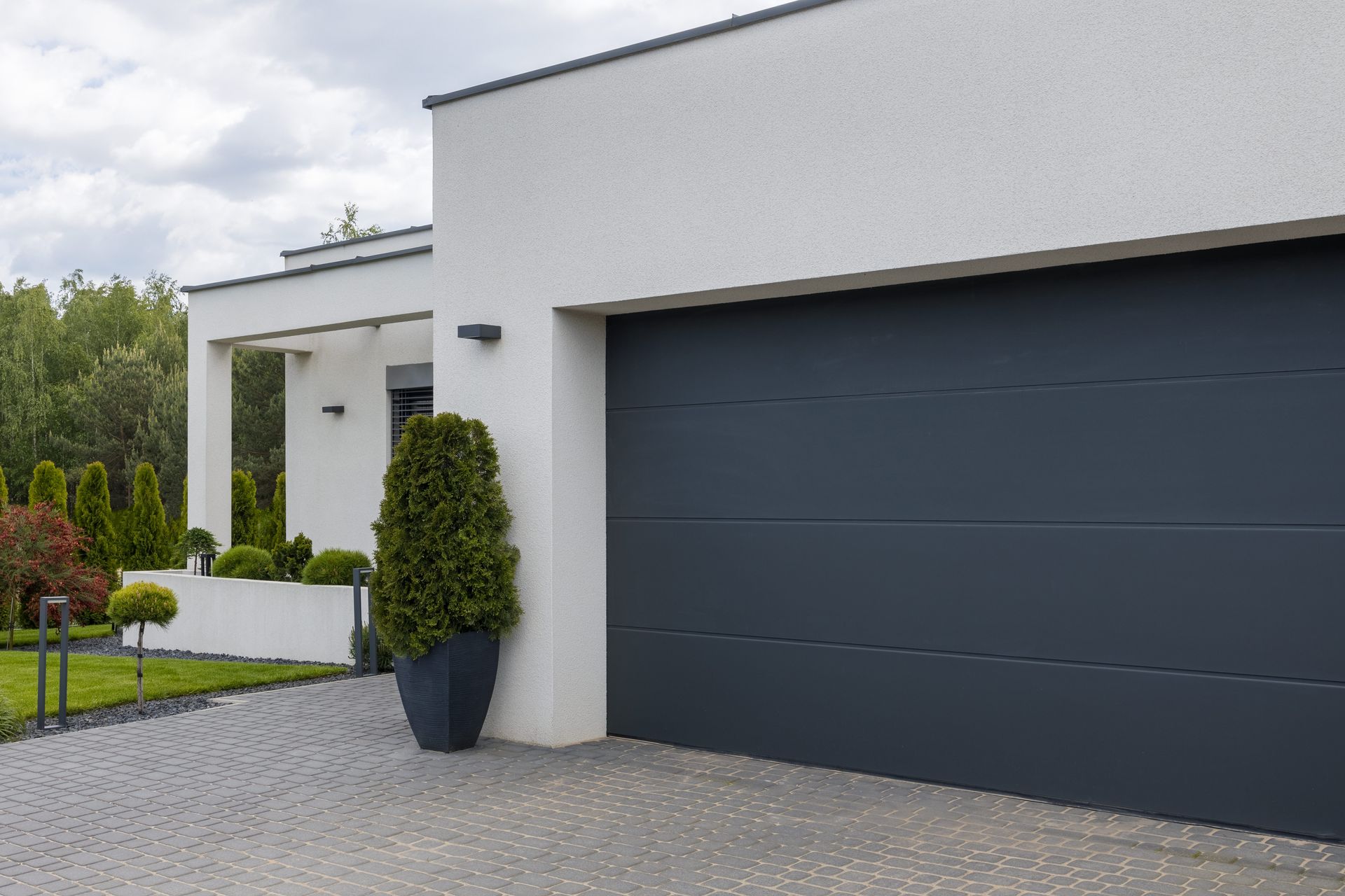 A white house with a black garage door and a driveway leading to it.
