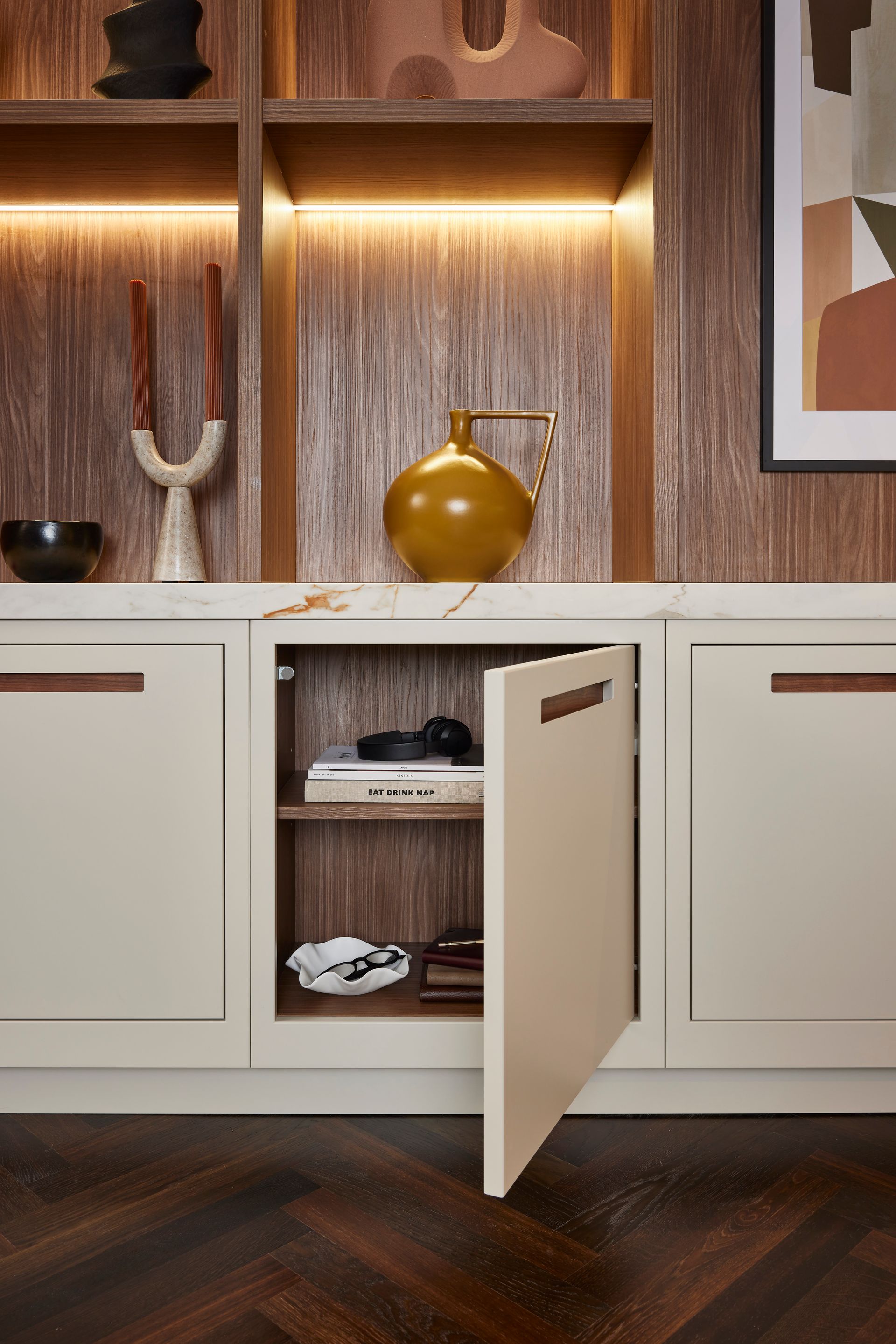 Open cabinet with shelves in a modern room, featuring cream cabinetry, a marble countertop, and decorative wood shelving.