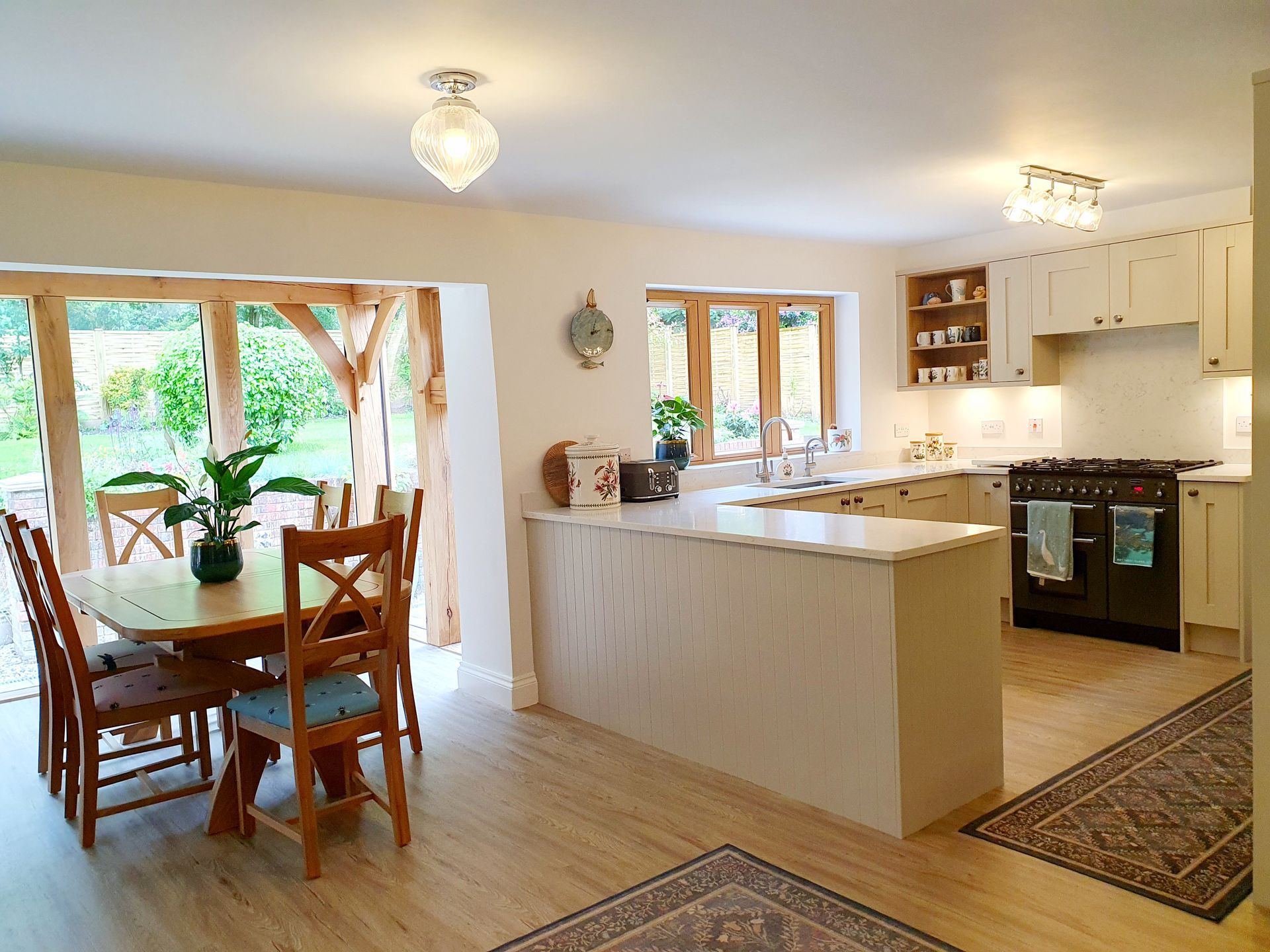 A bright open-plan kitchen and dining area featuring a wooden table, kitchen island, and modern stove.
