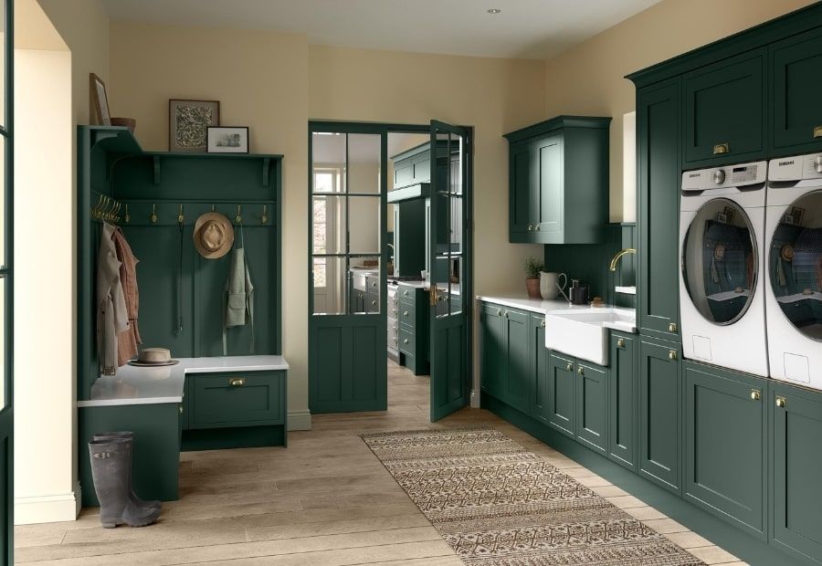 Dark green laundry room and mudroom with a white farmhouse sink, stacked washer and dryer, and a built-in bench.