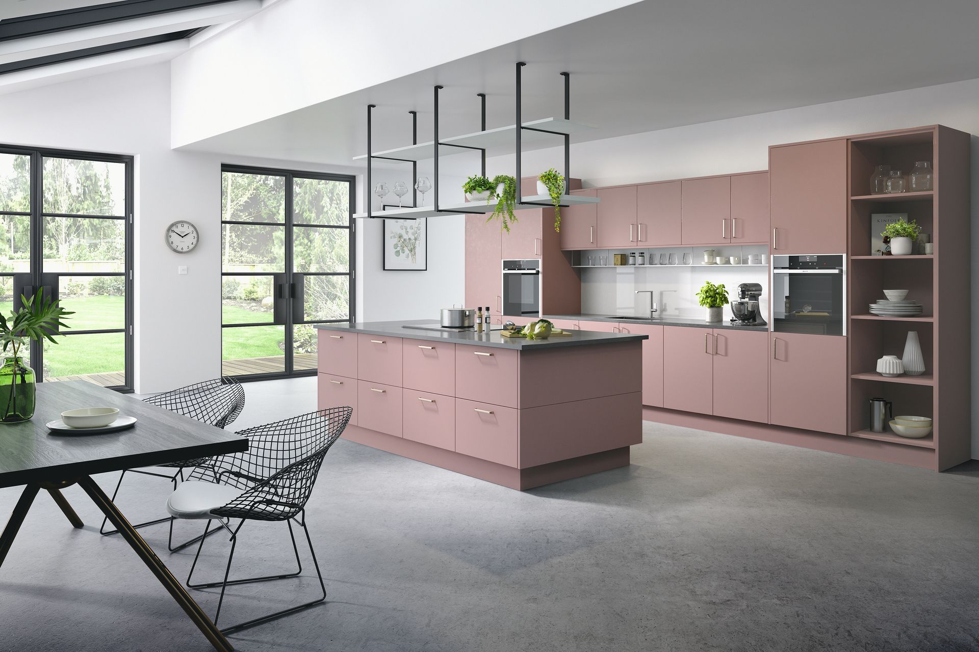 A modern, spacious kitchen with dusty pink cabinetry, a central island, and an open dining area with metal-framed windows.
