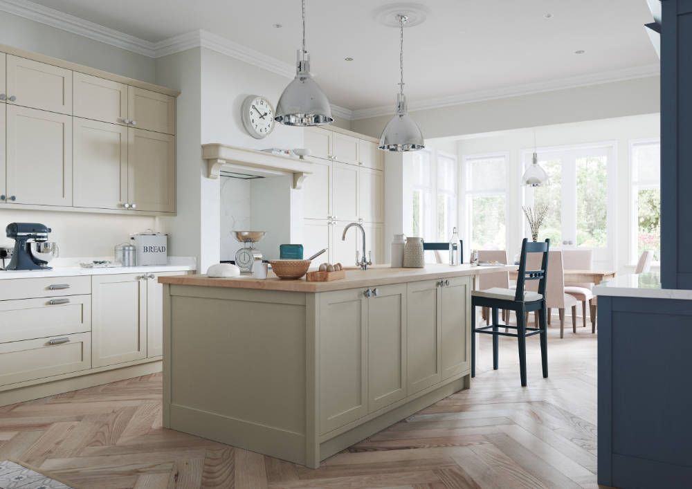 A modern kitchen featuring light beige cabinetry, a central island with a wooden countertop, and herringbone wood floors.