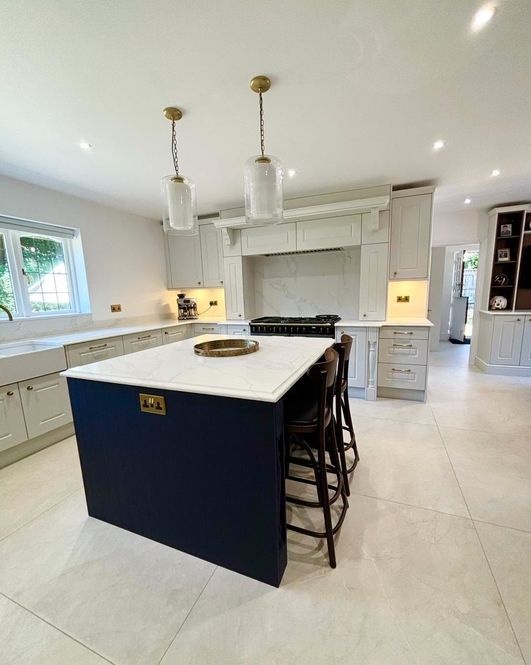Bright modern kitchen with white cabinets, island, pendant lights, and black bar stools