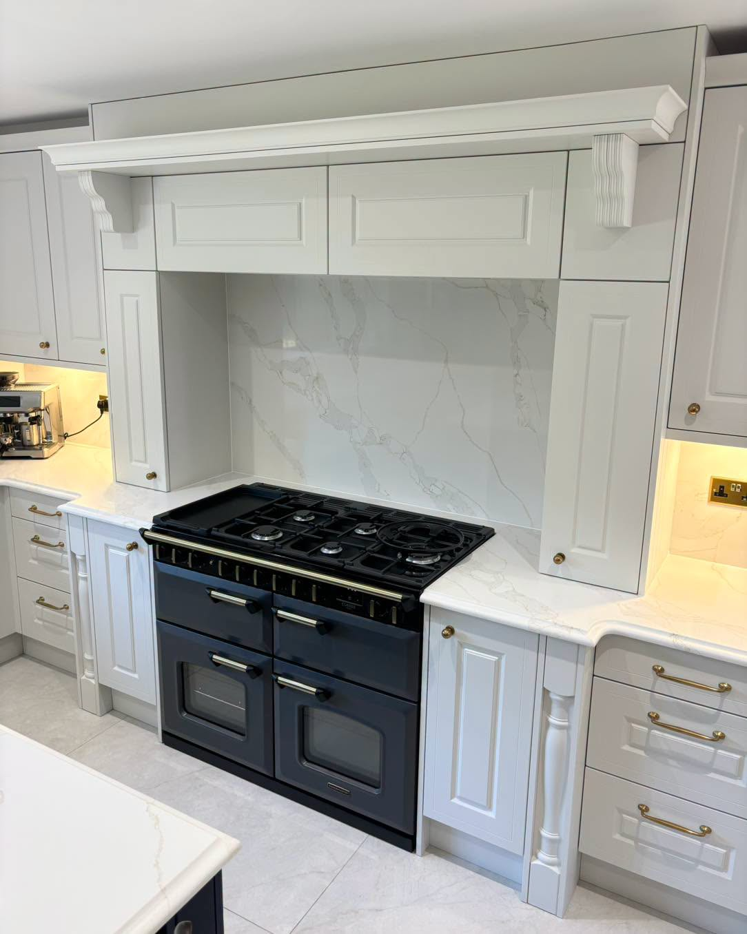 Modern kitchen with white cabinetry, black range, marble backsplash, and under-cabinet lighting