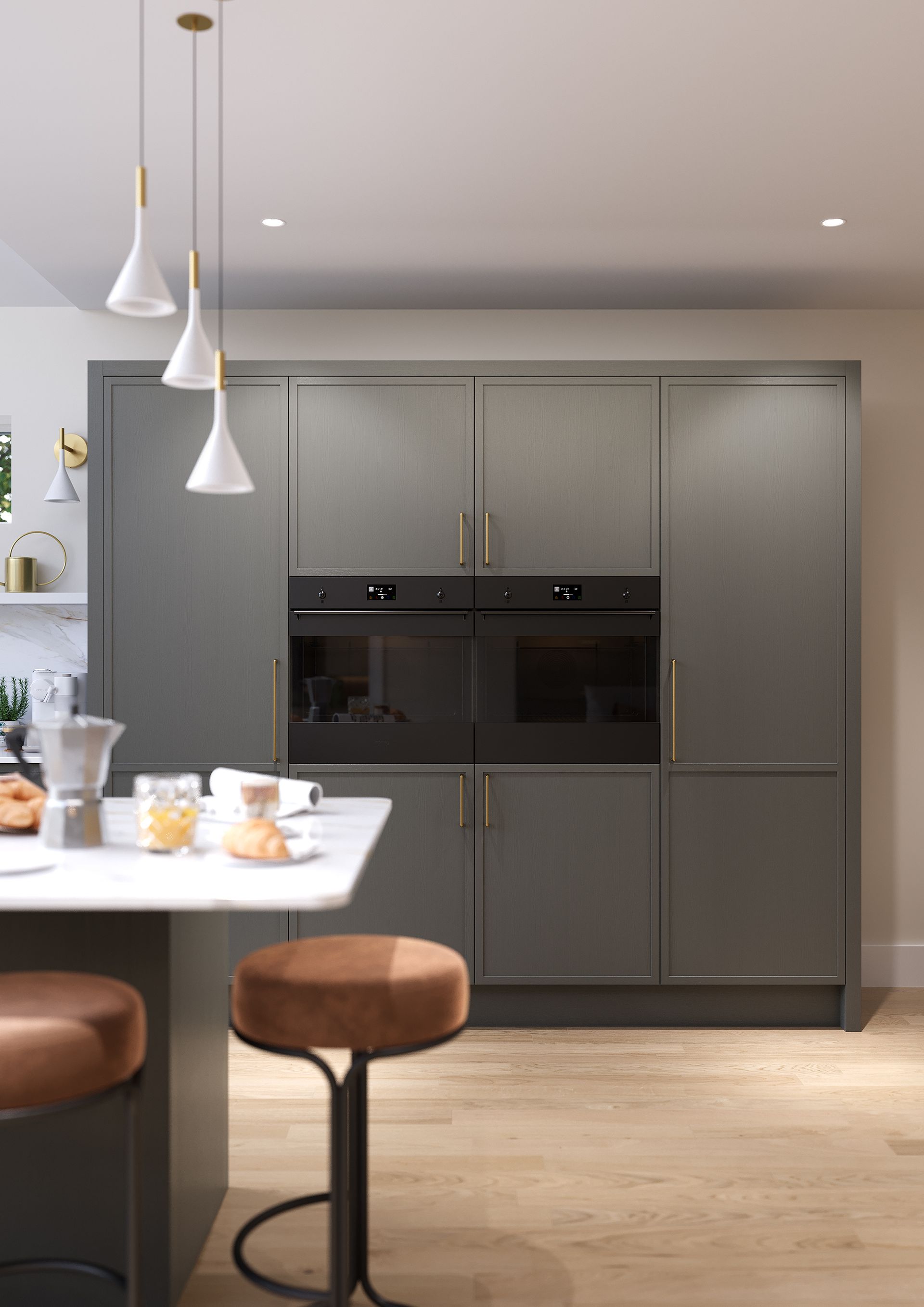 A modern kitchen with grey cabinetry, a built-in oven, pendant lights, and two bar stools at a white marble counter.