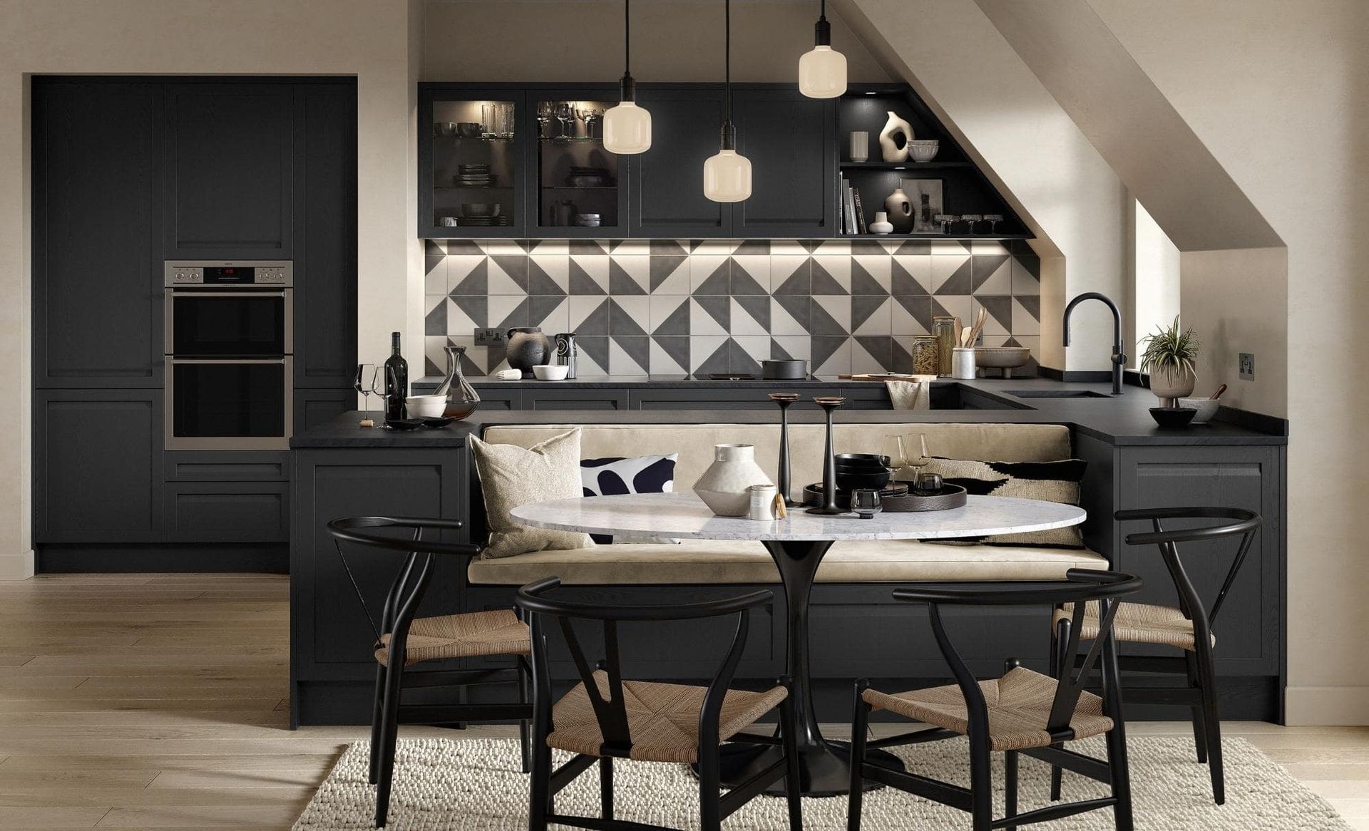 Modern black kitchen with built-in booth seating, round marble table, and geometric tile backsplash.