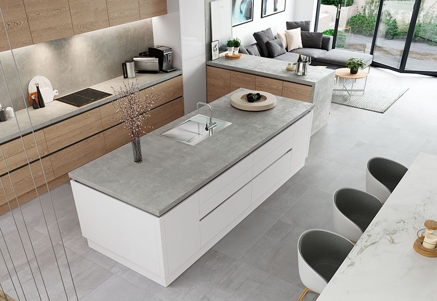 A high-angle view of a modern kitchen with white island, wood cabinets, grey stone countertops, and three grey bar stools.