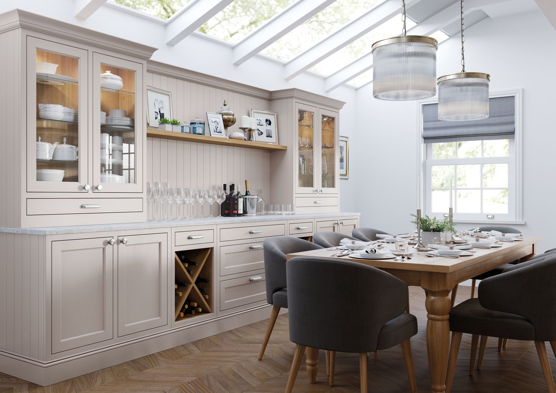 A dining room with a light beige buffet cabinet, wooden table, and grey upholstered chairs under a skylight.