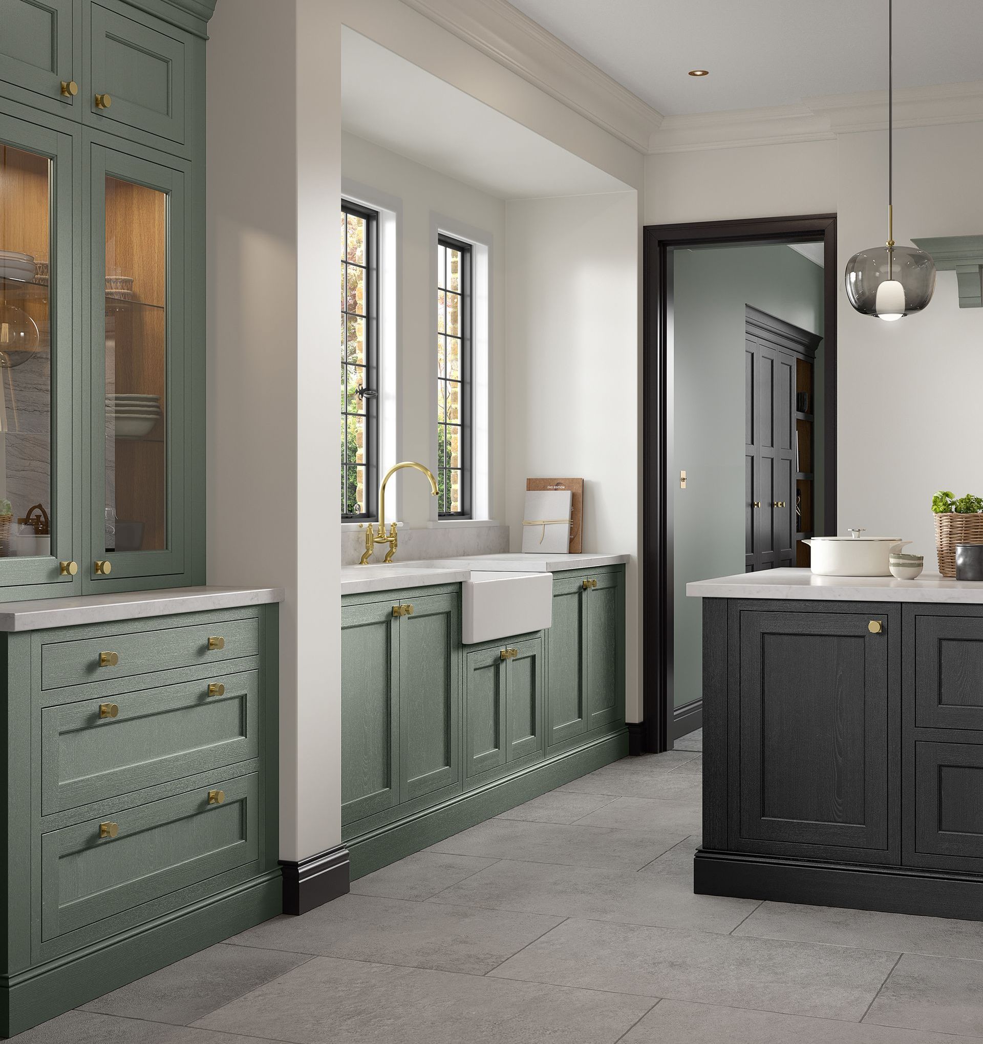 A modern kitchen featuring sage green cabinetry with brass hardware, a white farmhouse sink, and a dark kitchen island.