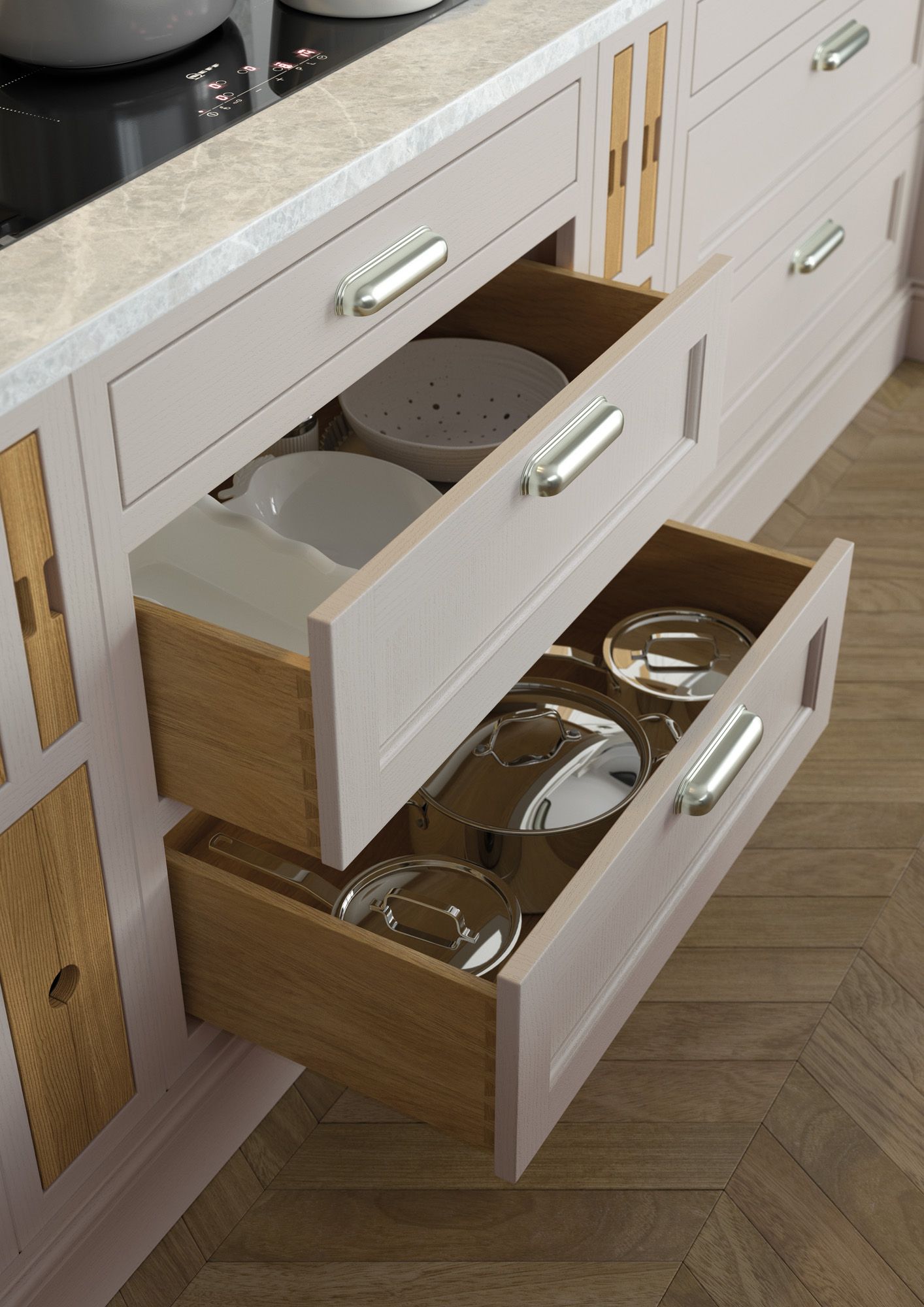 Two open, light-colored kitchen drawers containing bowls and pots, set into cabinetry with a marble countertop.