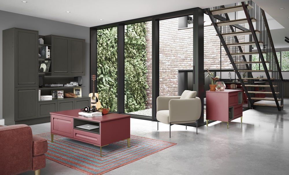 A modern living room with a red coffee table, a gray shelving unit, a cream armchair, and a staircase in a bright space.