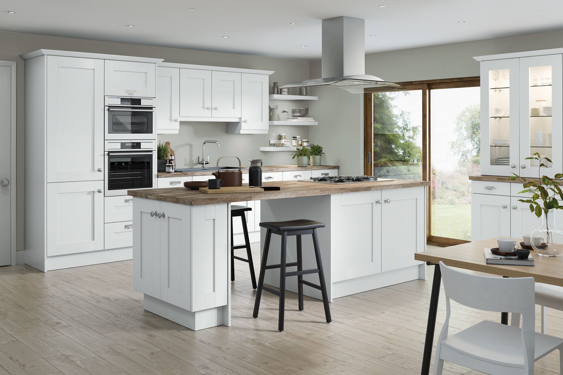 A bright, modern white kitchen with wood countertops, an island with bar stools, and a glass-paneled display cabinet.