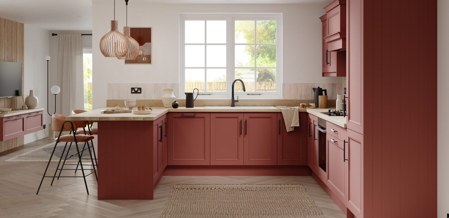 Modern kitchen with terracotta-colored cabinets, a U-shaped layout, a central window, and two pendant lights.