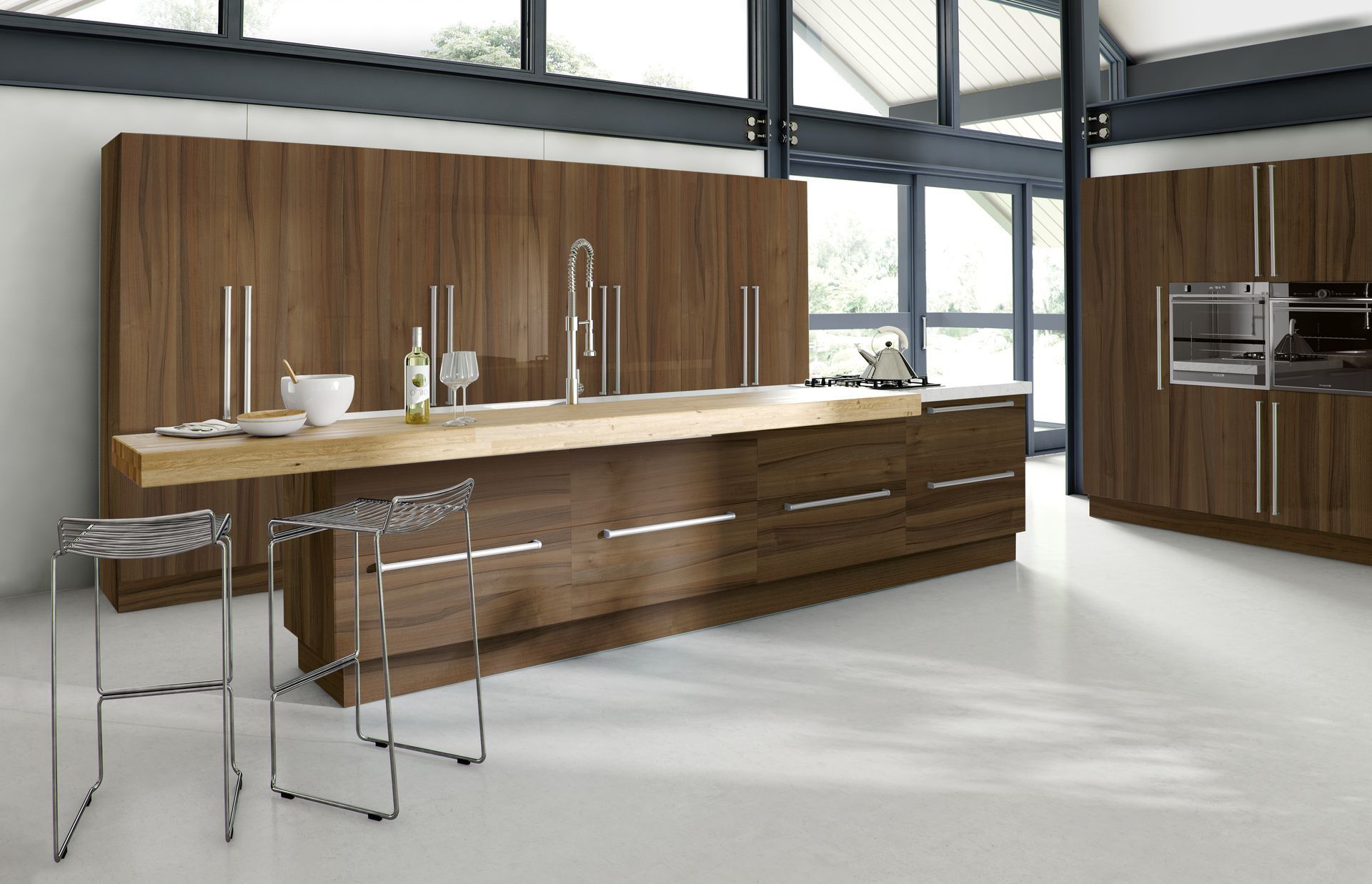 Modern kitchen with dark wood cabinetry, a long light-wood countertop, a stainless steel sink, and two mesh bar stools.